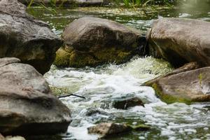 hermosas ondas en el flujo del río sobre piedras en verano foto