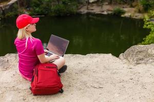 Woman using laptop showing blank screen on a beautiful beach on summer vacation photo