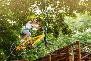 Happy school girl enjoying activity in a climbing adventure park on a summer day photo