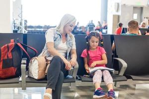 mamá y su hijo esperan su avión en el aeropuerto. los pasajeros están esperando su transporte en la estación foto