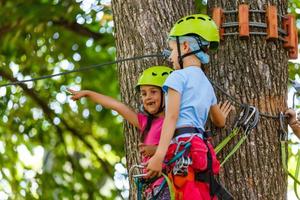 adventure climbing high wire park - children on course rope park in mountain helmet and safety equipment photo