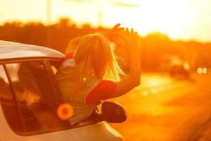 mujer feliz niña va a un viaje de verano en coche. foto