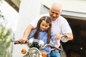 feliz abuelo y su nieta cerca de la bicicleta sonriendo foto