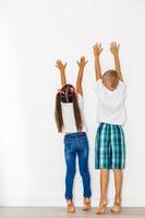 Little boy and girl measuring their height isolated on white background photo