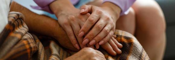 Young girl's hand touches and holds an old woman's wrinkled hands. photo