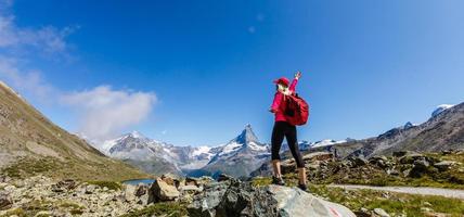 mujer en la cima de la montaña del paisaje montañoso alrededor del lago y el cielo azul. foto