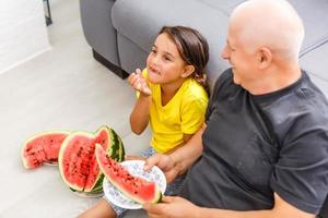grandfather and granddaughters eat watermelon at home photo