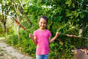 Little girl with pleasure eats shish kebab photo