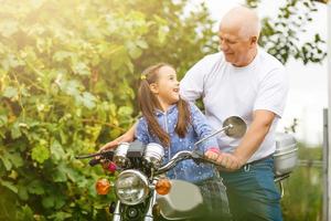 feliz abuelo y su nieta cerca de la bicicleta sonriendo foto