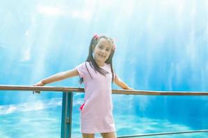 A little girl is looking fishes in a huge aquarium photo