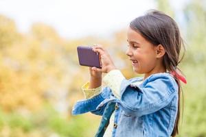 educación, escuela, tecnología y concepto de internet - niña estudiante con smartphone en el parque foto