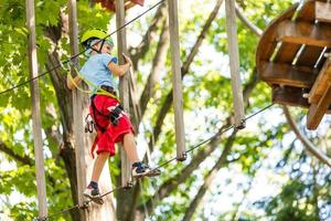 niños pequeños felices en un parque de cuerdas en el fondo de madera foto