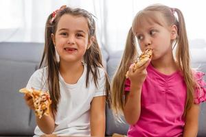 two girls eating pizza home photo