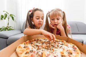 Portrait of cute little girl sitting and eating pizza photo