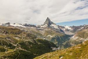 Hiking in the swiss alps with flower field and the Matterhorn peak in the background. photo