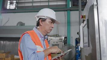 machine of onderhoud senior ingenieurs inspecteren machines en sterilisatoren in fabrieken of fabricage industrieën en schrijven naar beneden de informatie Aan tablet. machine en onderhoud concept. video