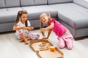 Portrait of cute little girl sitting and eating pizza photo