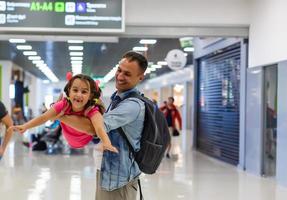 vamos a encontrar nuestro vuelo. vista de feliz padre e hija en el aeropuerto en la terminal foto