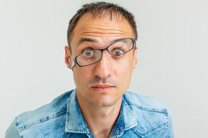 Closeup portrait of frustrated, mad angry nerdy young man with big glasses, screaming fists raised, isolated on white background. Negative emotions facial expressions feelings, body language photo