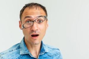 A goofy man wearing trendy nerd glasses isolated over white with a funny expression on his face. photo