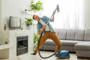 Coronavirus pandemic. A man with a vacuum cleaner in his apartment. Home Office. Quarantine. Remote work. A man in a business shirt and underpants holds. photo