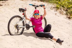 Young sexy blonde girl with long hair in sunglasses standing near bicycle, have fun and good mood looking in camera and smiling photo