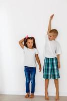 Little boy and girl measuring their height isolated on white background photo