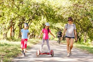 Small girl learns to ride electric mini hoverboard in the city. photo