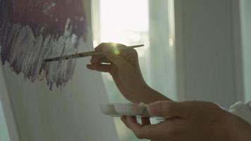un artiste professionnel en gros plan utilise un pinceau dans l'art abstrait pour créer un chef-d'œuvre. peinture de peintre à l'aquarelle ou à l'huile dans la maison de studio. la femme aime peindre comme passe-temps. travail loisirs video