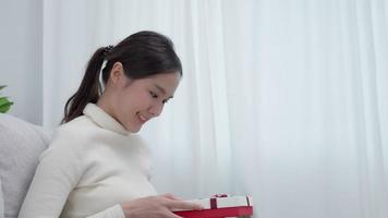 hübsche asiatische frau fühlt sich überrascht und sieht interesse in der geschenkbox aus. süßes Mädchen aufgeregt offene Geschenkbox. geburtstag, feier, weihnachten, neujahrsfest, danken, feiern, valentinstag, jahrestag video
