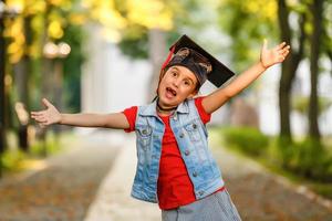 niño de escuela feliz graduado en gorra de graduación mirando hacia arriba foto