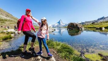 Happy hiker woman and girl at mountains lake photo