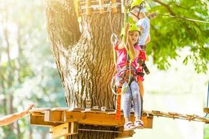 adventure climbing high wire park - children on course rope park in mountain helmet and safety equipment photo