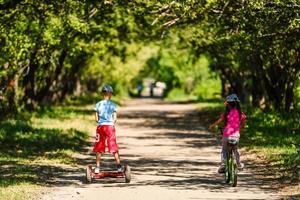 Girl on a bicycle and a boy on a gyroscope are riding together photo