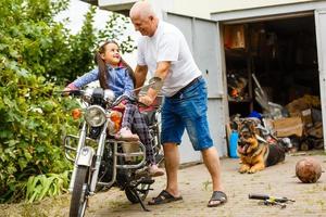 feliz abuelo y su nieta cerca de la bicicleta sonriendo foto