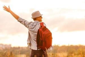 Getting away from it all. Man in open field relaxing looking at the beautiful view. photo