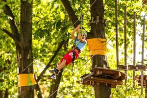 niños pequeños felices en un parque de cuerdas en el fondo de madera foto