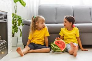 Two girls eating Watermelon isolated on home background photo