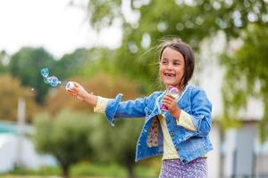 Little girl blowing soap bubbles photo