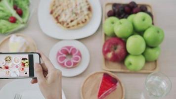 net idol e tirar foto para revisão de comida. as mulheres usam telefones celulares para tirar fotos de comida ou gravar vídeos ao vivo em aplicativos de redes sociais. comida para o almoço parece apetitosa. video