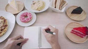 Concept of avoiding fat for diet. woman is losing weight and writes the word Fat on her notebook to remind her of weight loss. Fat foods or snacks cause obesity. video