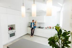 retrato de una pareja amorosa sonriente cocinando ensalada juntos mientras están de pie en una cocina en casa foto