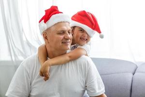 Close-up portrait of joyful girl hugging grandpa in headwear. grandfather and granddaughter in Santa Claus hats photo