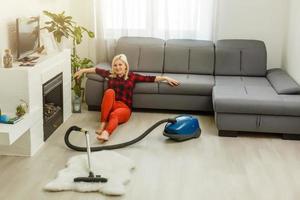 people, housework and technology concept - happy woman with tablet pc computer and robot vacuum cleaner drinking tea at home photo