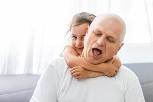 Funny lifestyle portrait of grandchild embracing grandfather photo