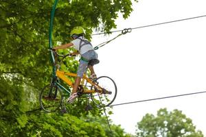 Portrait of little smiling girl in helmet and harness on trail in sky rope park in summer. photo