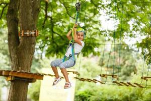 Adorable little girl enjoying her time in climbing adventure park on warm and sunny summer day photo