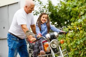 feliz abuelo y su nieta cerca de la bicicleta sonriendo foto