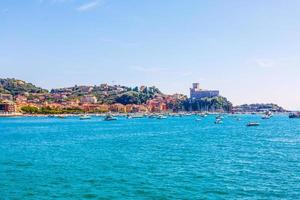 barcos de pesca amarrados en el agua en el puerto del mar mediterráneo y ligur cerca de la costa de riviera di levante del parque nacional cinque terre costa con cielo azul, pueblo de riomaggiore, liguria, italia. foto