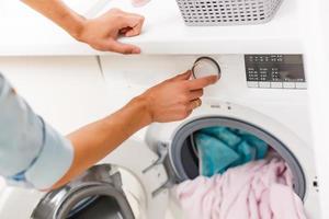 A detail of a male putting in a load of laundry photo